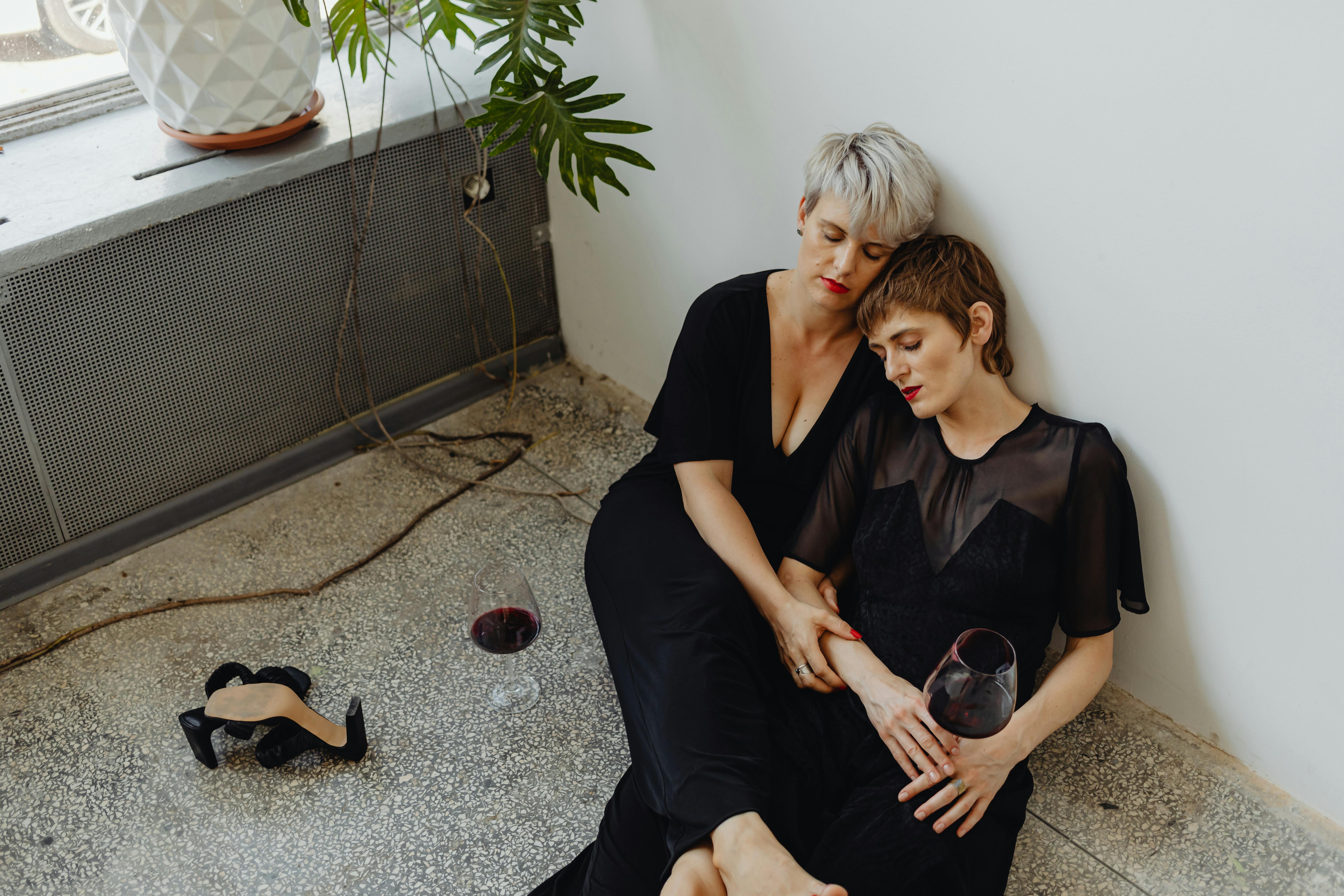 woman in black dress sitting on floor beside woman in black dress