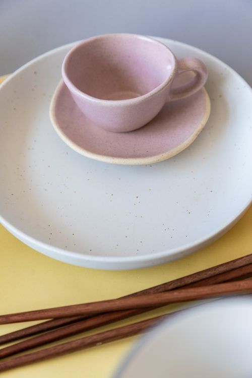 Free A minimalist pink ceramic teacup on a matching saucer and plate, styled with chopsticks. Stock Photo