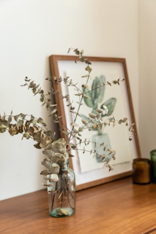 Eucalyptus Leaves in Glass Vase and Painting on Wooden Table