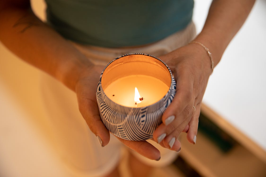 A Person Holding a Lighted Candle in a Container