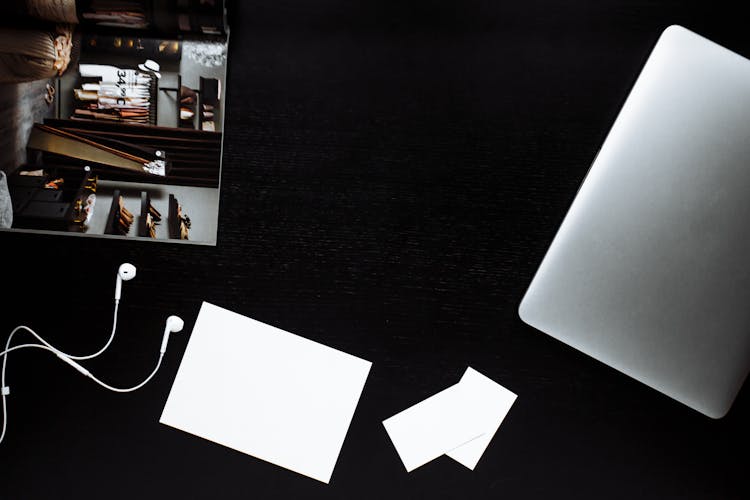 White Paper And Earphones Beside A Digital Tablet On Black Surface