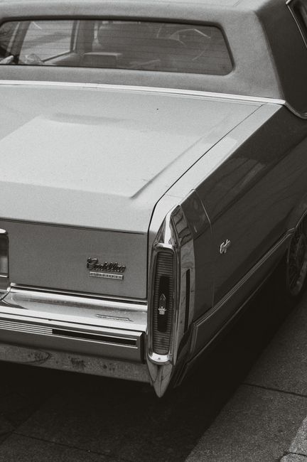 Classic black and white photograph of a vintage Cadillac's rear view, focusing on tail light and trunk.