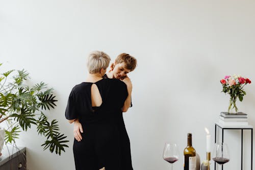 Woman in Black Dress Standing beside White Wall