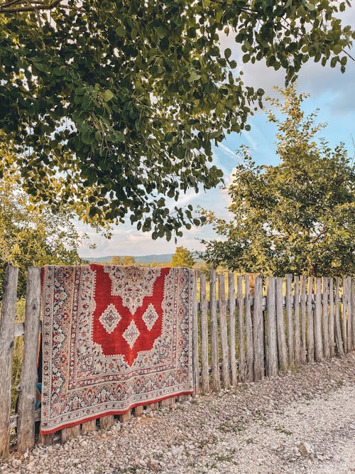 Red and White Carpet Hanging on the Wooden Fence
