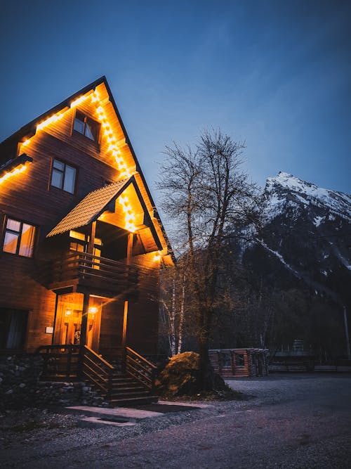 Illuminated Wooden Building Near Snow Capped Mountain