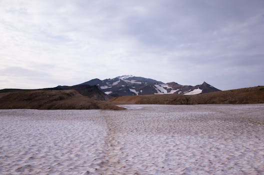 Expansive view of mountains with snow patches under a cloudy sky, showcasing the beauty of nature.