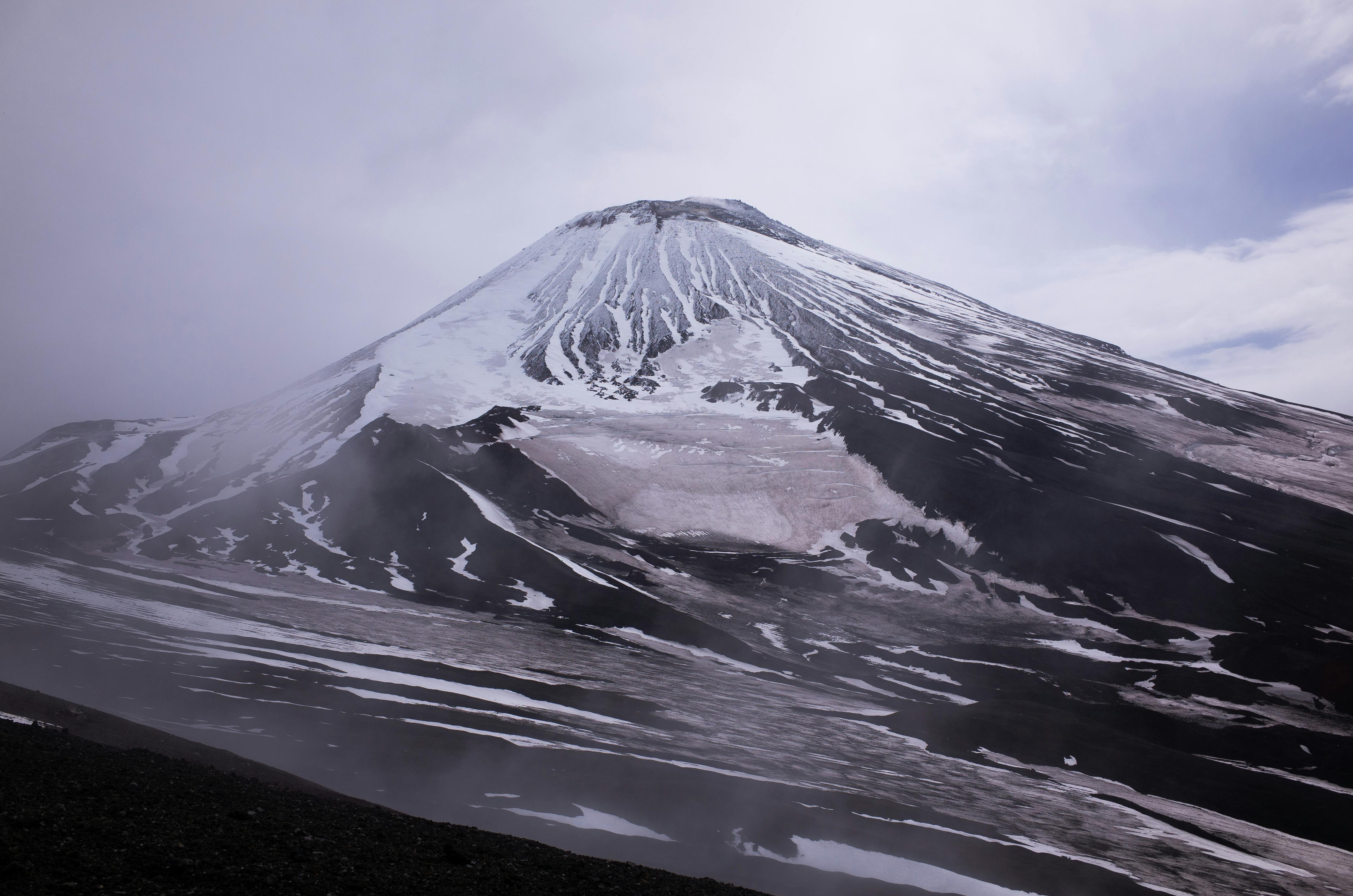 Prescription Goggle Inserts - Stunning view of a snow-covered volcanic mountain under cloudy skies.