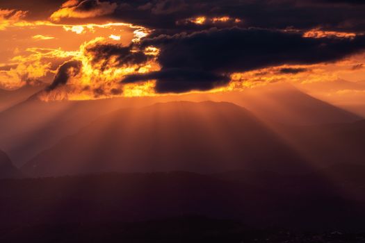 Majestic sunset over Sochi mountains with sunrays and clouds creating a dramatic effect.