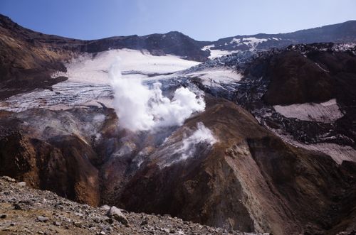 Free A breathtaking view of a steaming volcanic crater with snow-capped mountain peaks. Stock Photo