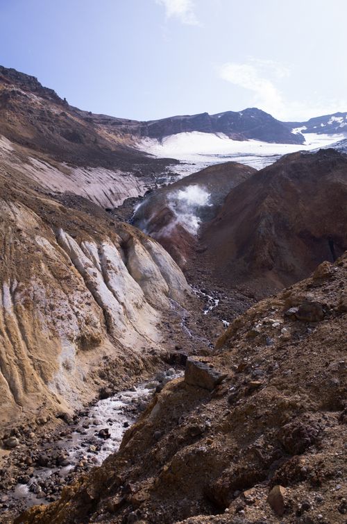 Free Scenic view of volcanic terrain with steam rising, showcasing rugged geology and blue sky. Stock Photo