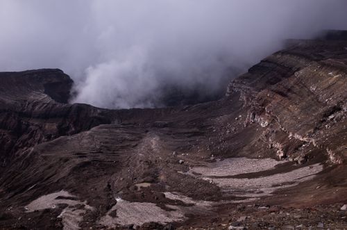 Free Misty volcanic crater shown in dense fog, capturing dramatic rugged terrain. Stock Photo