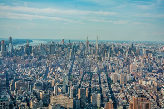 Breathtaking aerial shot of New York City skyline with iconic skyscrapers and Hudson River under a blue sky.