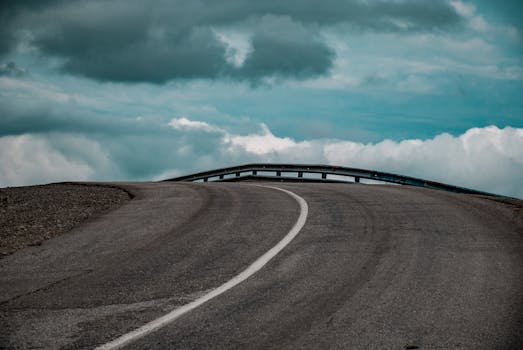 A winding highway stretches under a dramatic cloudy sky, offering a sense of journey and solitude.