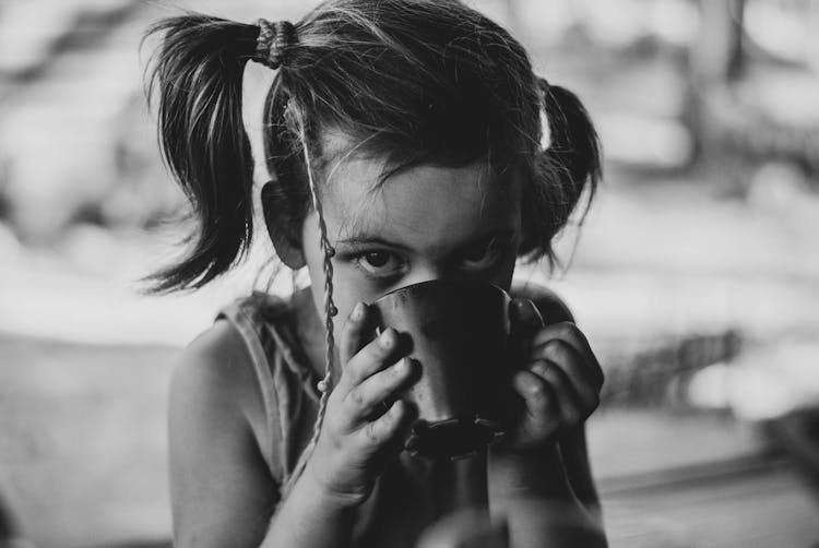 Grayscale Photo Of A Girl Drinking From A Cup