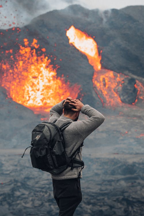 A Man in Gray Jacket Standing Near the Erupting Volcano