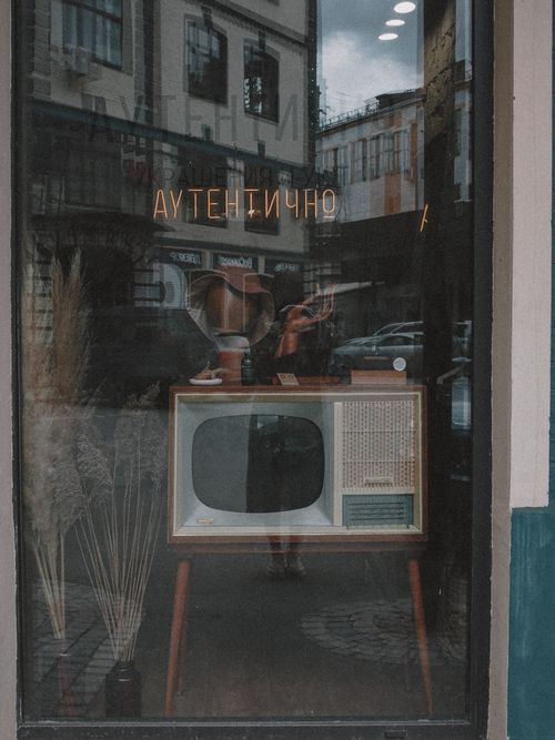 Free A vintage television set displayed in a shop window with reflections of the street outside. Stock Photo