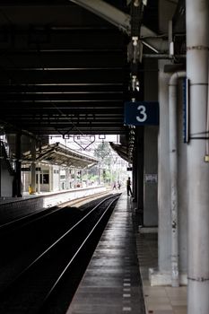 An empty train station platform with tracks and industrial architecture.