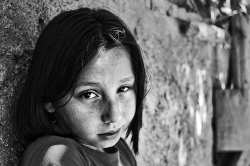 Free Emotive black and white portrait of a young girl leaning against a textured wall. Stock Photo