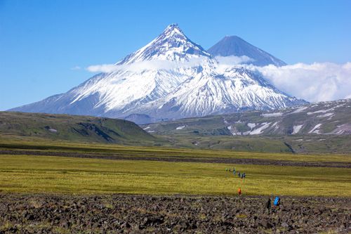 Free Snow-capped mountain peaks with expansive grassland in the foreground on a sunny day. Stock Photo