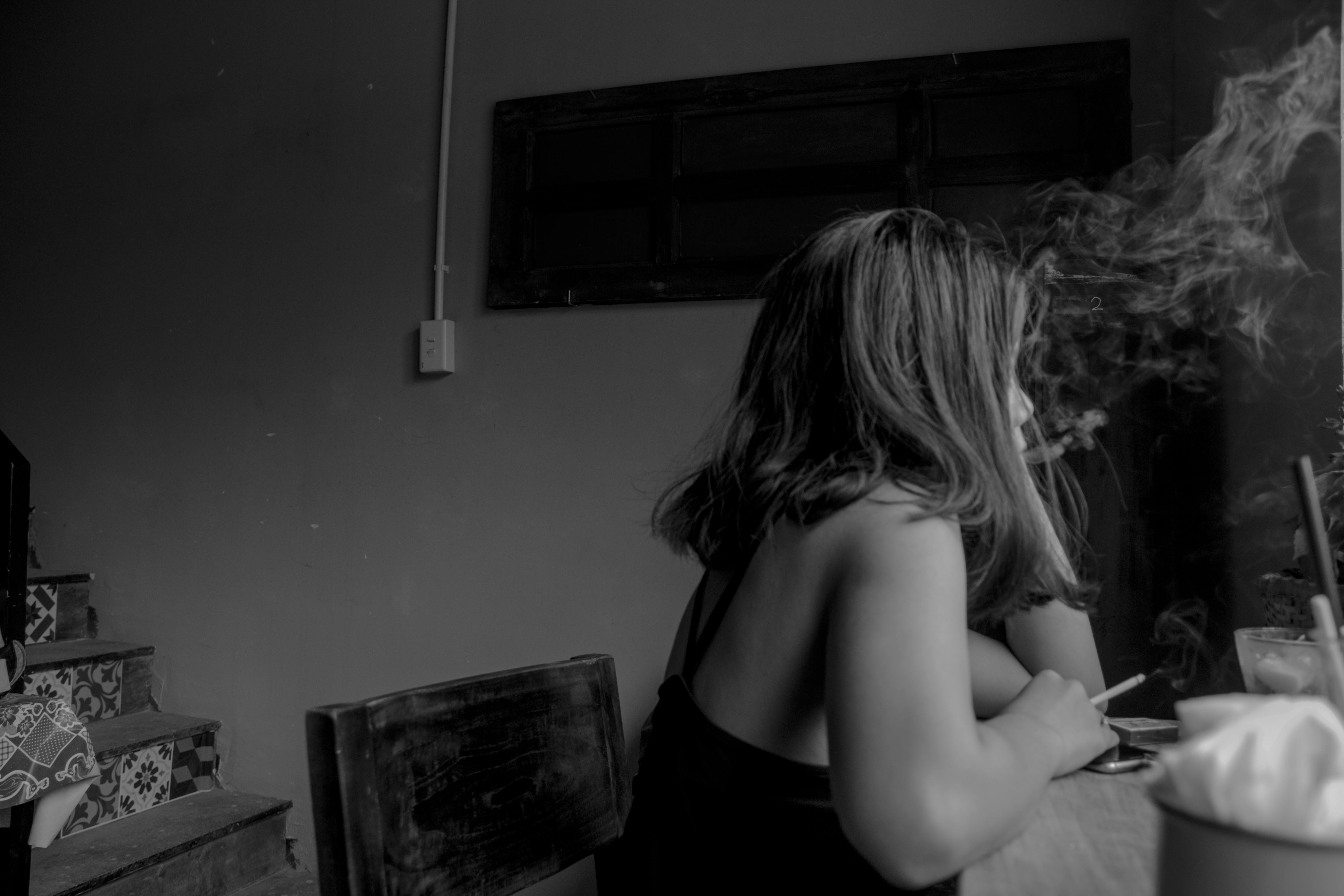 grayscale photo of woman sitting on chair near chair