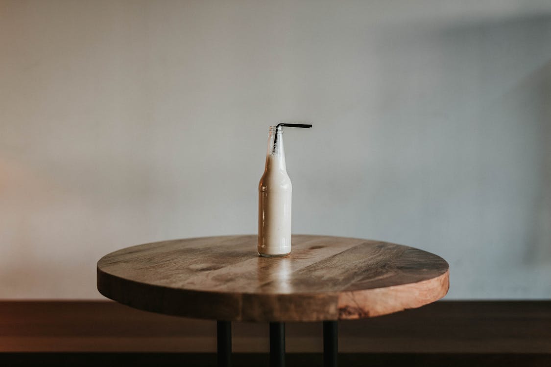 Free Glass Bottle Filled With Black Straw on Brown Wooden Table Stock Photo