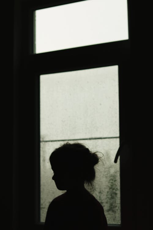 Grayscale Photo of Person Looking at Window