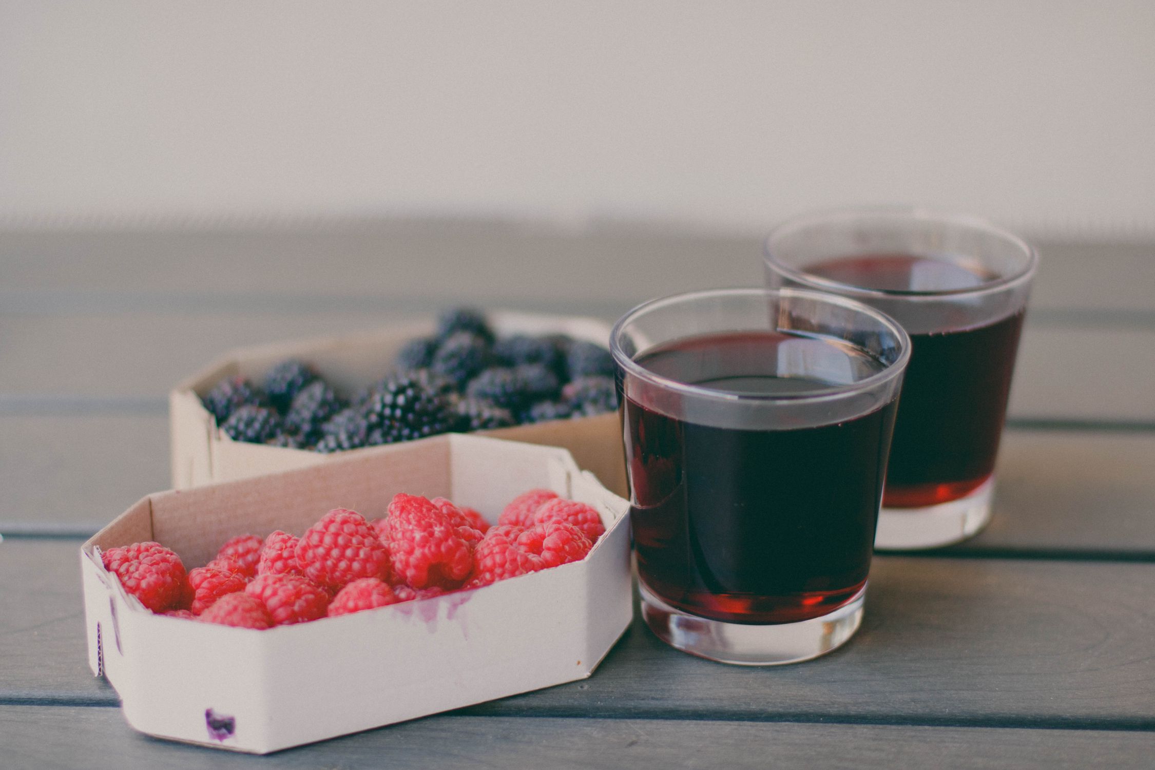 Two Drinking Glasses Filled With Raspberry and Blueberry Fruit Juices ...
