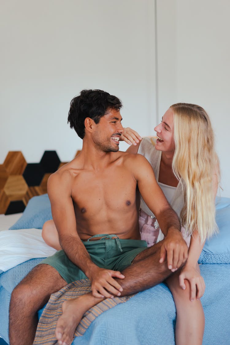 Topless Man And Woman Sitting On Bed