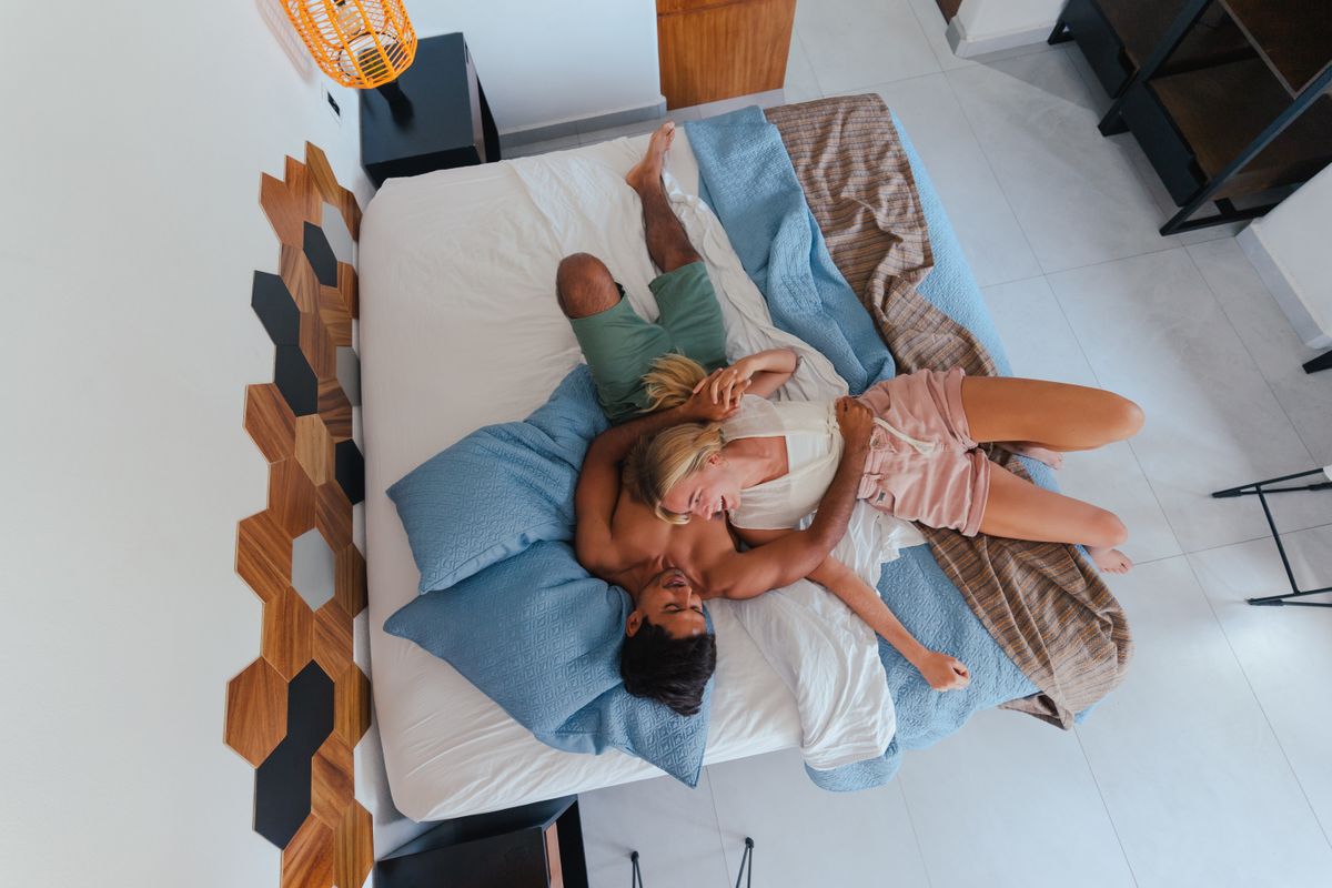 A relaxed, happy couple cuddling together in a bright modern bedroom