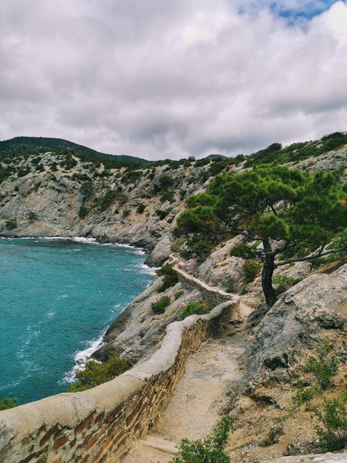 Free Explore a rocky coastal path along a scenic cliff with vibrant greenery and a clear blue sea. Stock Photo