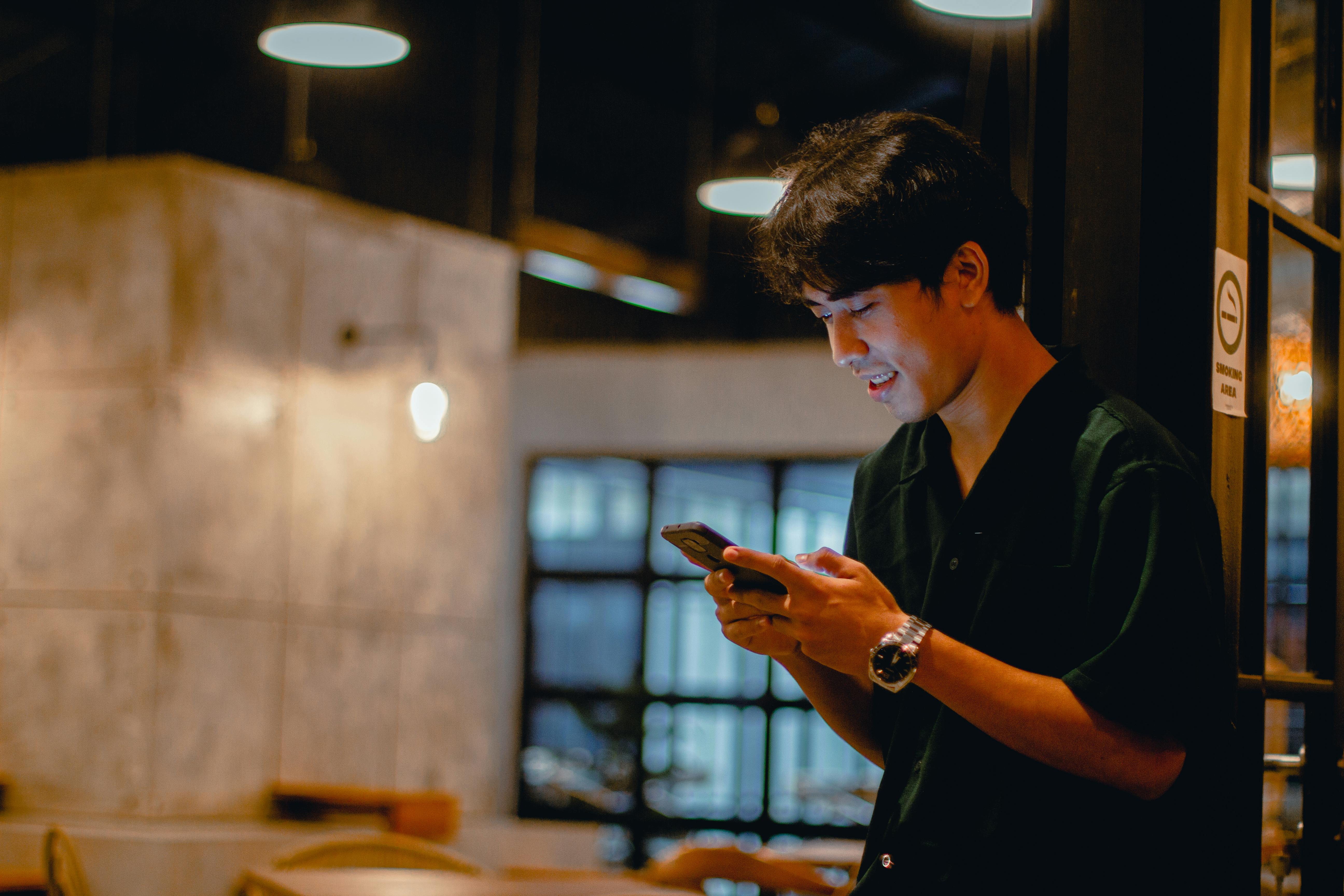 man in black polo shirt using a smartphone