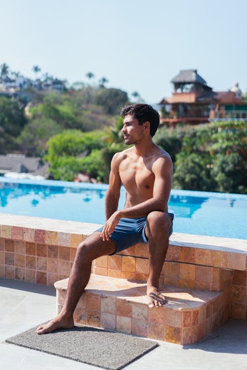 Free Man in Blue Shorts Sitting onTiled Poolside Stock Photo