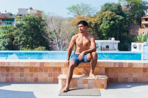Free Topless Man in Shorts Sitting on the Tiled Pooside Stock Photo