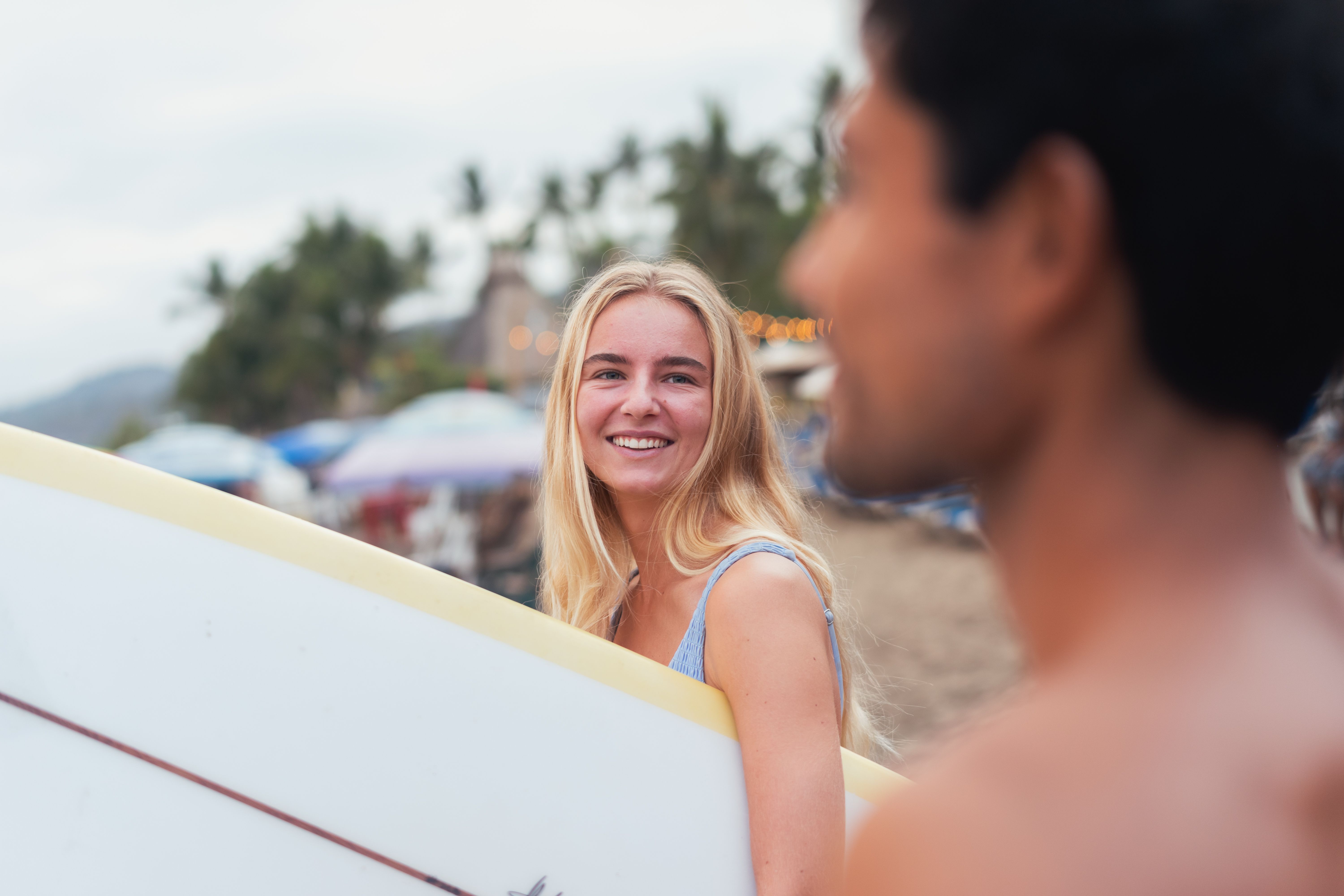 A young woman and man with surfboards enjoying a sunny day at the beach.