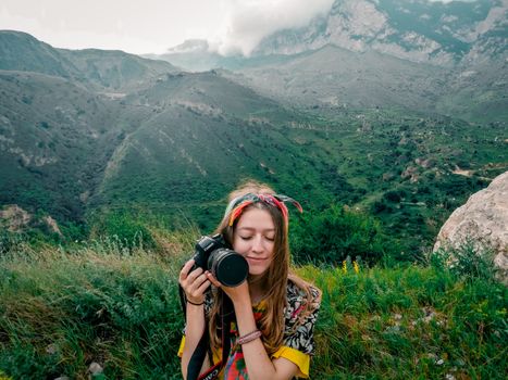 Young woman enjoying serenity with camera amidst the lush Caucasus mountains.