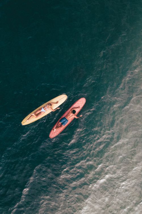 Free A stunning aerial view of two kayakers paddling on a calm sea, captured in the beauty of summer. Stock Photo