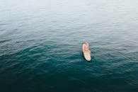 航拍照片中一名女子坐在平静的大海中冲浪板上