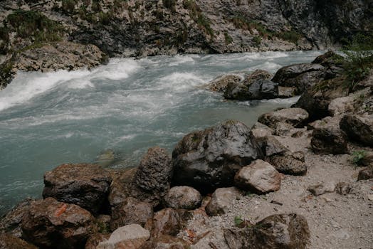 A pristine mountain river flows over rugged rocks, showcasing natural beauty and geology.