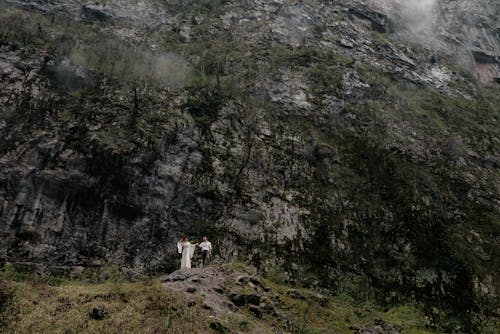 Woman in White Dress and Man Walking in the Mountains 