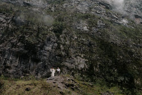 Woman in White Dress and Man Walking in the Mountains 