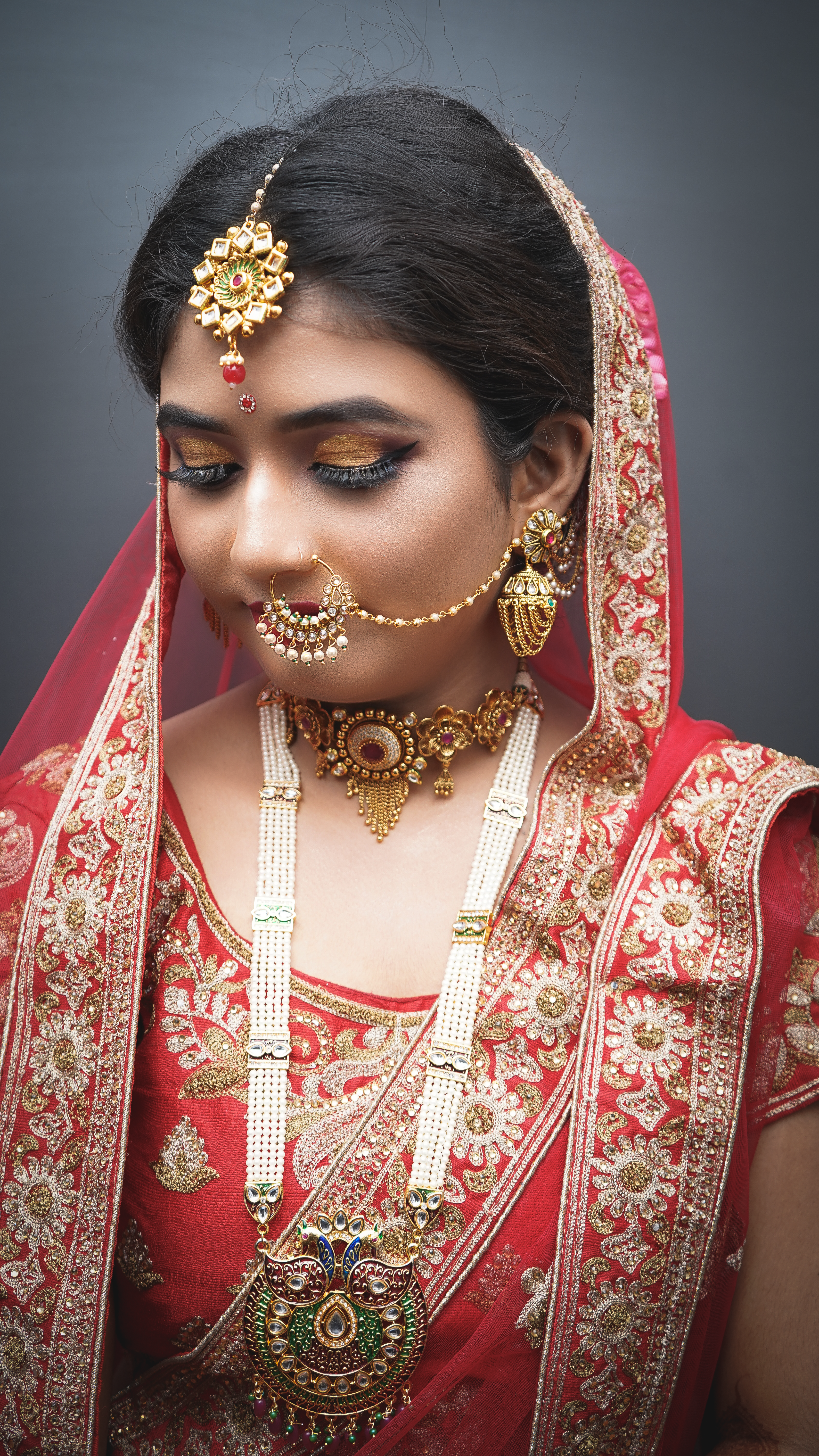 Close-up portrait of a South Asian bride adorned with intricate jewelry and a vibrant red bridal gown.