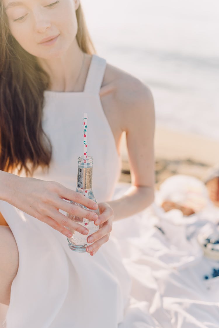 A Woman Holding A Bottle With Straw