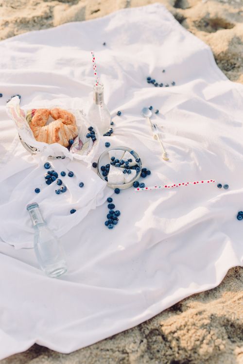 Free A serene outdoor picnic featuring croissants and blueberries on a white blanket. Stock Photo