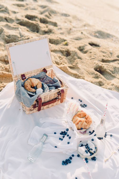 Free Enjoy a sunny beach picnic with croissants and fresh blueberries, perfect for a relaxing day outdoors. Stock Photo