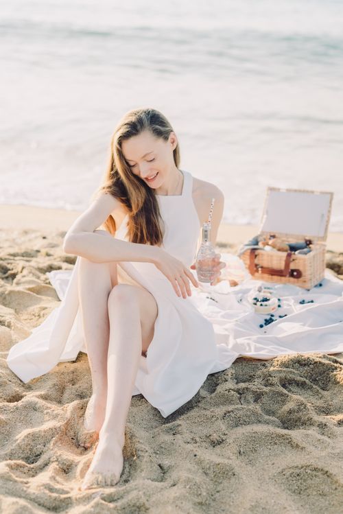 Free Relaxing beach picnic with a woman in a white dress on a sunny day. Stock Photo