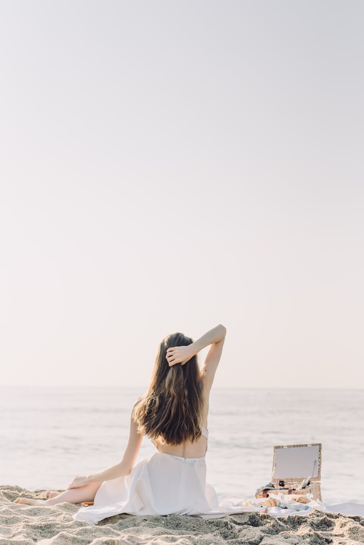 Back View Of A Woman Sitting On The Beach 