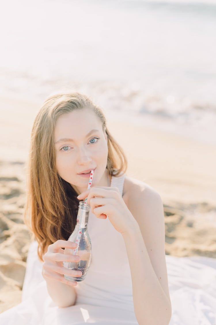 A Woman With A Bottle Of Drink On The Beach