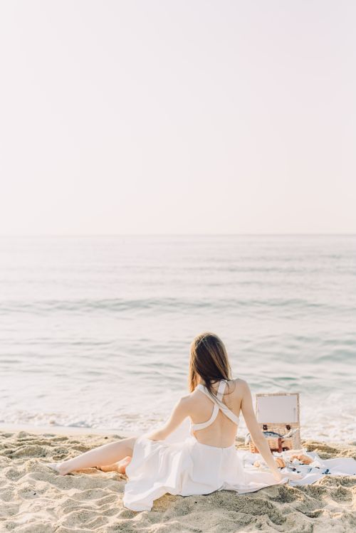 Free Woman enjoying a peaceful picnic on the beach during a bright summer day. Stock Photo