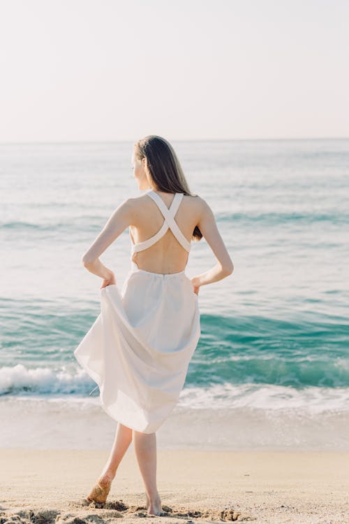 Back View of Woman in White Dress Standing on the Seashore