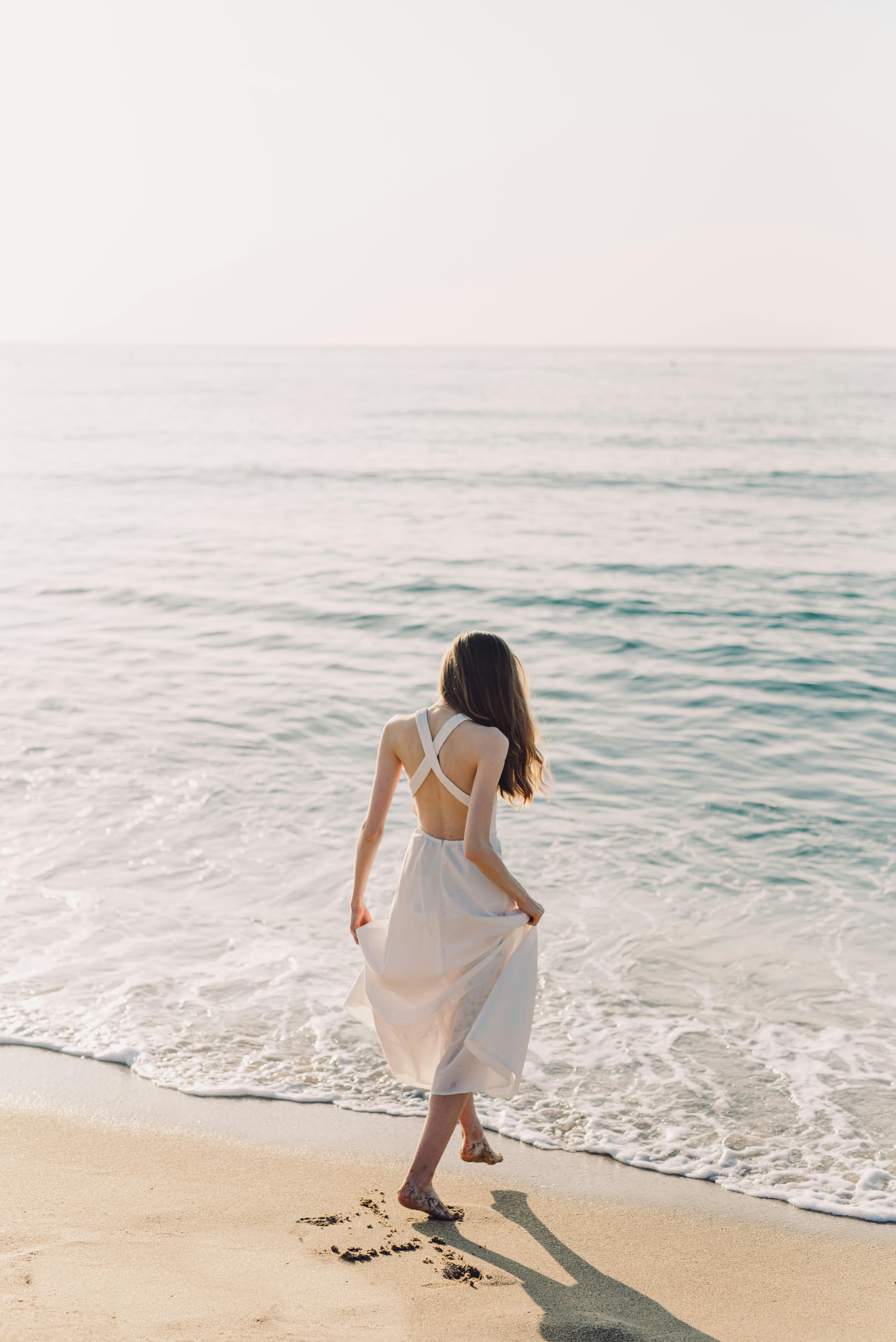 A Woman in White Dress Walking on the Beach · Free Stock Photo